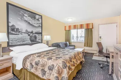 a hotel room with a bed and a desk at Super 8 by Wyndham Stettler in Stettler