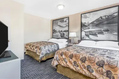 a hotel room with two beds and a flat screen tv at Super 8 by Wyndham Stettler in Stettler