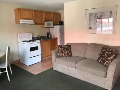 a living room with a couch and a kitchen at SlumberLodge Hotel in Penticton