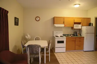 a small kitchen with a table and a white refrigerator at SlumberLodge Hotel in Penticton