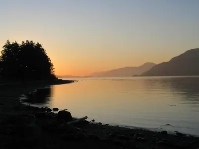 a sunset on the shore of a body of water at Alert Bay Lodge in Alert Bay