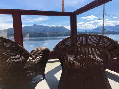 two chairs sitting on a porch looking out at the water at Alert Bay Lodge in Alert Bay