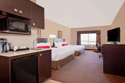 a hotel room with two beds and a kitchen at Ramada by Wyndham Stettler in Stettler