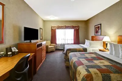 a hotel room with two beds and a flat screen tv at Canalta Stettler in Stettler