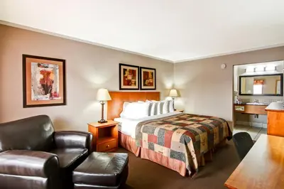 a hotel room with a bed and a chair at Canalta Stettler in Stettler