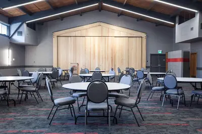 an empty room with tables and chairs and a large screen at Best Western Plus Tin Wis Resort in Tofino