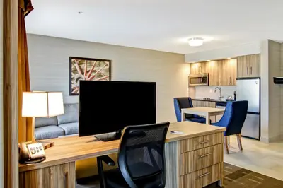 a room with a desk with a television and a kitchen at Canalta St.Paul in St. Paul