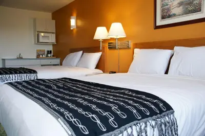 two beds in a hotel room with white pillows at R&R Inn & Suites in Camrose