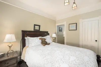 a teddy bear sitting on a bed in a bedroom at O Canada House Bed & Breakfast in Vancouver