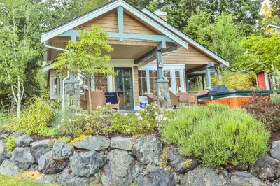 a house with a stone wall in front of it at Poets Cove Resort & Spa in Bedwell Harbour