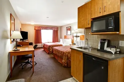 a hotel room with a bed and a desk and a kitchen at Canalta Rocky Mountain House in Rocky Mountain House