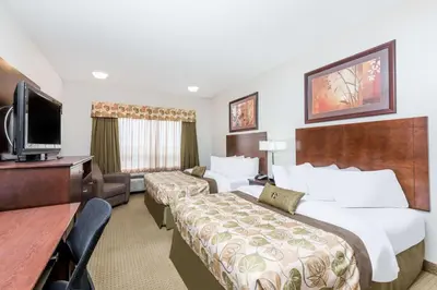 a hotel room with two beds and a flat screen tv at Ramada by Wyndham Olds in Olds