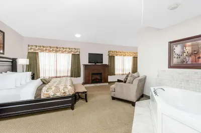 a bedroom with a bed and a tv and a tub at Ramada by Wyndham Olds in Olds