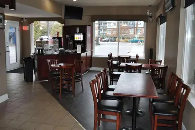a restaurant with wooden tables and chairs and a counter at Travelodge by Wyndham Langley in Langley