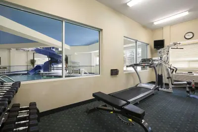 a room with a gym with a treadmill and a swimming pool at Travelodge by Wyndham Strathmore in Strathmore