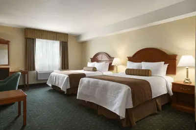 a hotel room with two beds and a chair at Travelodge by Wyndham Strathmore in Strathmore