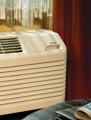 a white air conditioner sitting next to a curtain at New Horizon Motel in Christina Lake