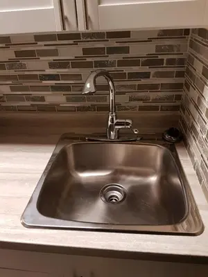 a stainless steel sink in a kitchen with a brick wall at Holiday Motel & RV Resort in Hope