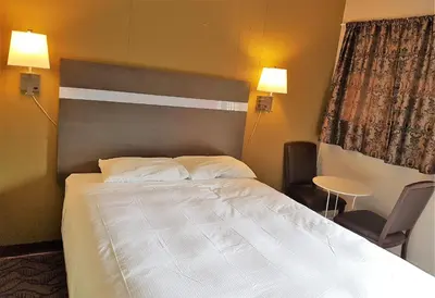 a bedroom with a bed and a chair and a table at Holiday Motel & RV Resort in Hope