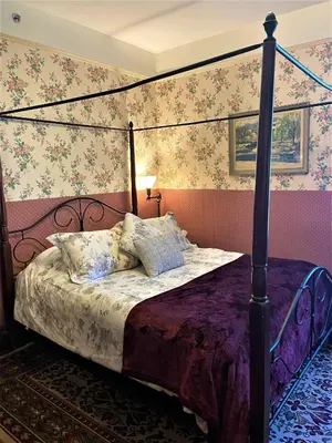 a bedroom with a canopy bed with a purple comforter at Marketa's Bed and Breakfast in Victoria