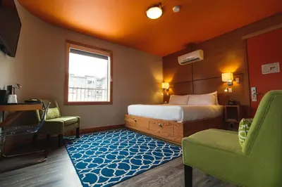a bedroom with a bed and a chair and a window at Adventure Hotel in Nelson