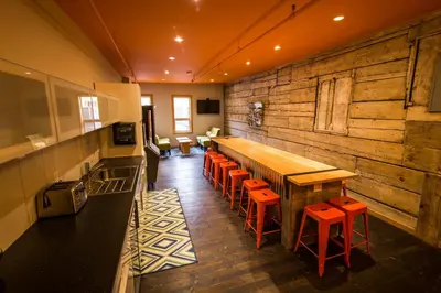 a kitchen with a long bar with orange stools at Adventure Hotel in Nelson