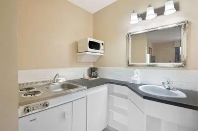 a white bathroom with a sink and a mirror at Deer Park Inn in Red Deer