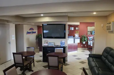 a waiting room with tables and a flat screen tv at Deer Park Inn in Red Deer