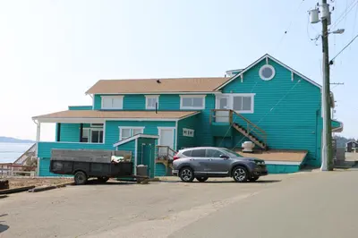 a truck parked in front of a blue house at Nimpkish Hotel in Alert Bay