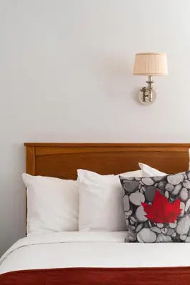 a bed with white pillows and a lamp on top at Schott's Lake Conference & Resort in Sundre