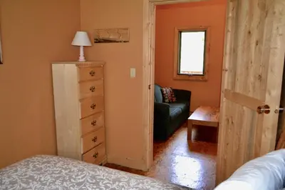 a bedroom with a door open to a living room at Schott's Lake Conference & Resort in Sundre