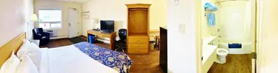 a bedroom with a bed and a desk with a television at Grande Mountain Lodge in Grande Cache