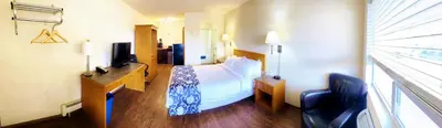 a hotel room with a bed and a desk and a window at Grande Mountain Lodge in Grande Cache
