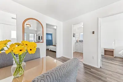 a white living room with a vase of yellow flowers on a table at 5000 Motel in Penticton