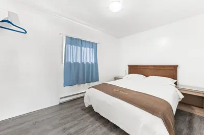 a white bedroom with a bed and a window at 5000 Motel in Penticton