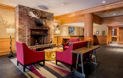 a lobby with red chairs and a fireplace at Whistler Village Inn & Suites in Whistler