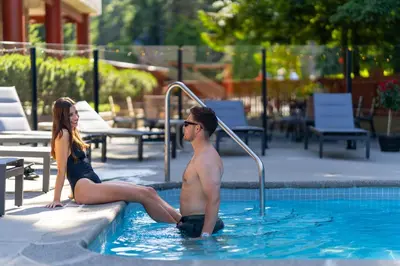 a man and woman sitting in a swimming pool at Whistler Village Inn & Suites in Whistler