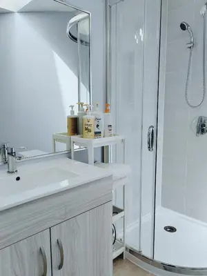 a white bathroom with a shower and a sink at Bed Plus YVR in Richmond