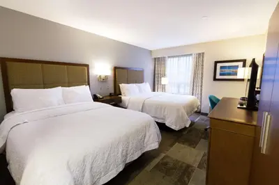 a hotel room with two beds and a television at Hampton Inn - Vancouver Airport/Richmond in Richmond