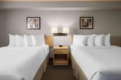 two beds in a hotel room with white pillows at Travelodge by Wyndham Fort McMurray in Fort McMurray