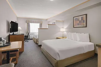 a hotel room with a large bed and a desk at Travelodge by Wyndham Fort McMurray in Fort McMurray