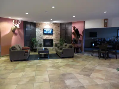 a lobby with couches and a fireplace and a bar at Sigma Inn & Suites Hudson's Hope in Hudson Hope