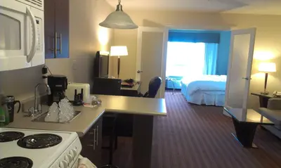 a room with a kitchen and a bedroom with a bed at Sigma Inn & Suites Hudson's Hope in Hudson Hope