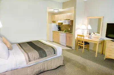 a hotel room with a bed and a desk and a kitchen at Clearwater Suite Hotel in Fort McMurray