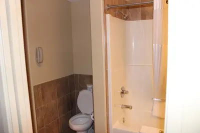 a bathroom with a white toilet and a shower at Clearwater Suite Hotel in Fort McMurray