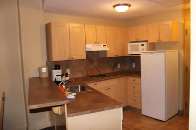 a kitchen with wooden cabinets and a white refrigerator at Clearwater Suite Hotel in Fort McMurray