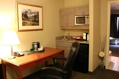 a hotel room with a desk and a kitchen at Nomad Hotel & Suites in Fort McMurray