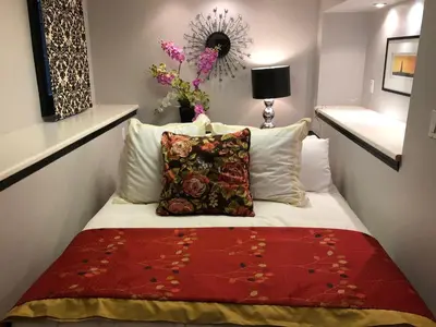 a small bedroom with a bed with a red blanket at Barclay House Bed and Breakfast in Vancouver