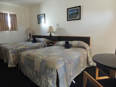 a hotel room with two beds and a table at 100 Mile Motel & RV Park in One Hundred Mile House