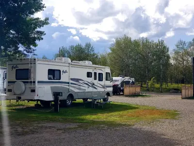 an rv parked in a field next to a tent at 100 Mile Motel & RV Park in One Hundred Mile House
